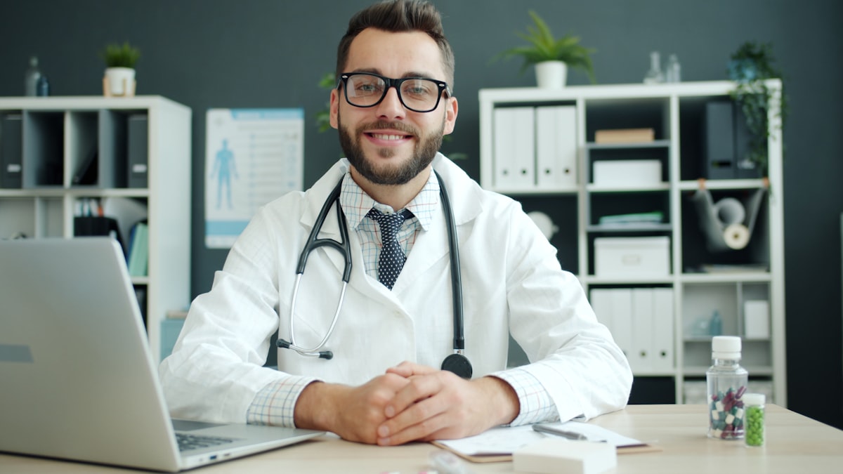 Médico de jaleco com estetoscópio à mesa do consultório, representando tráfego pago para médicos